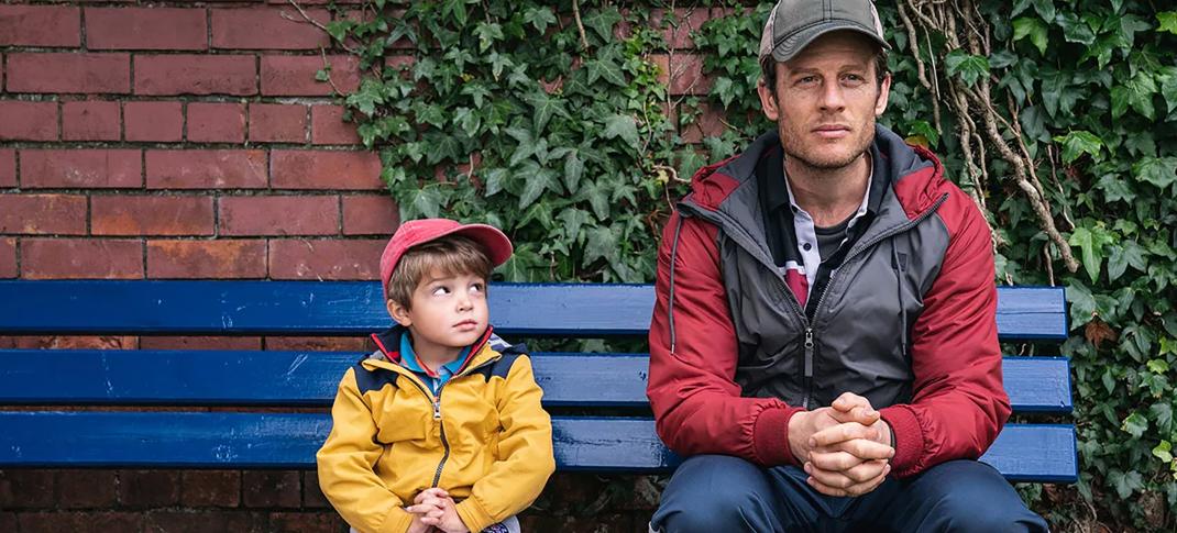 Daniel Lamont as Michael and James Norton as John sit together on a bench in 'Nowhere Special'